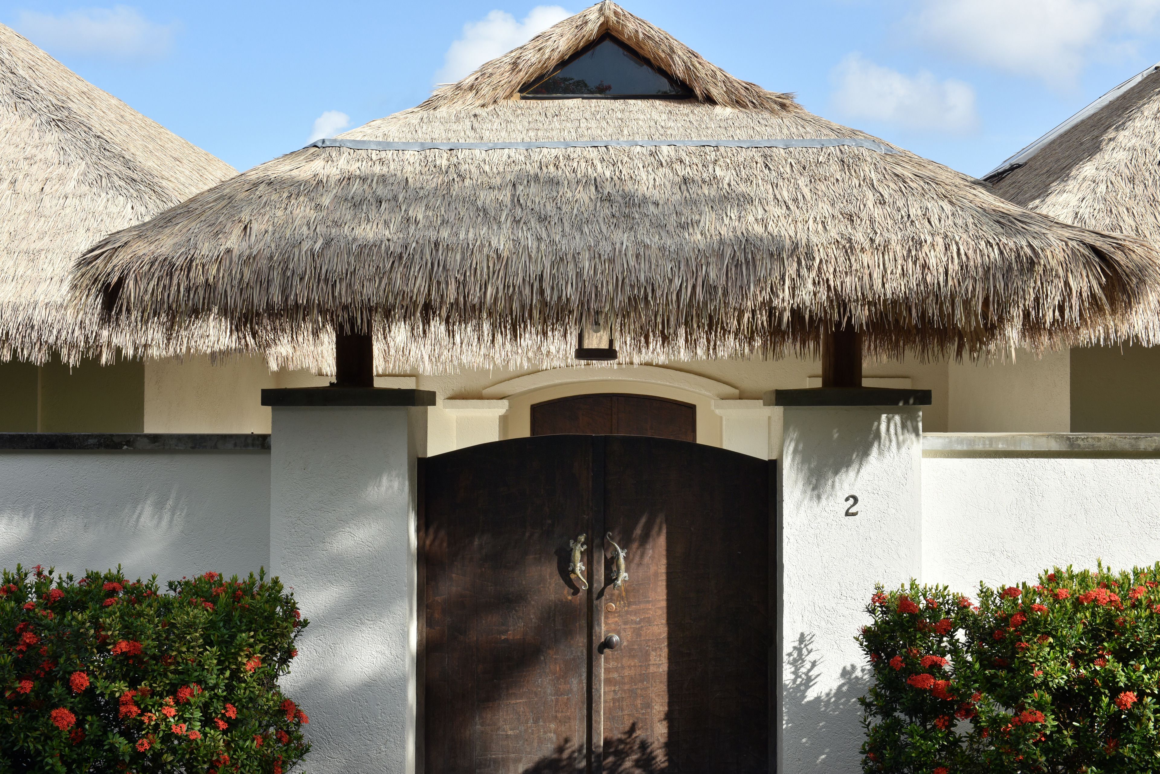 A building with a thatched roof, a dark wooden door, and a number '2' on the wall.