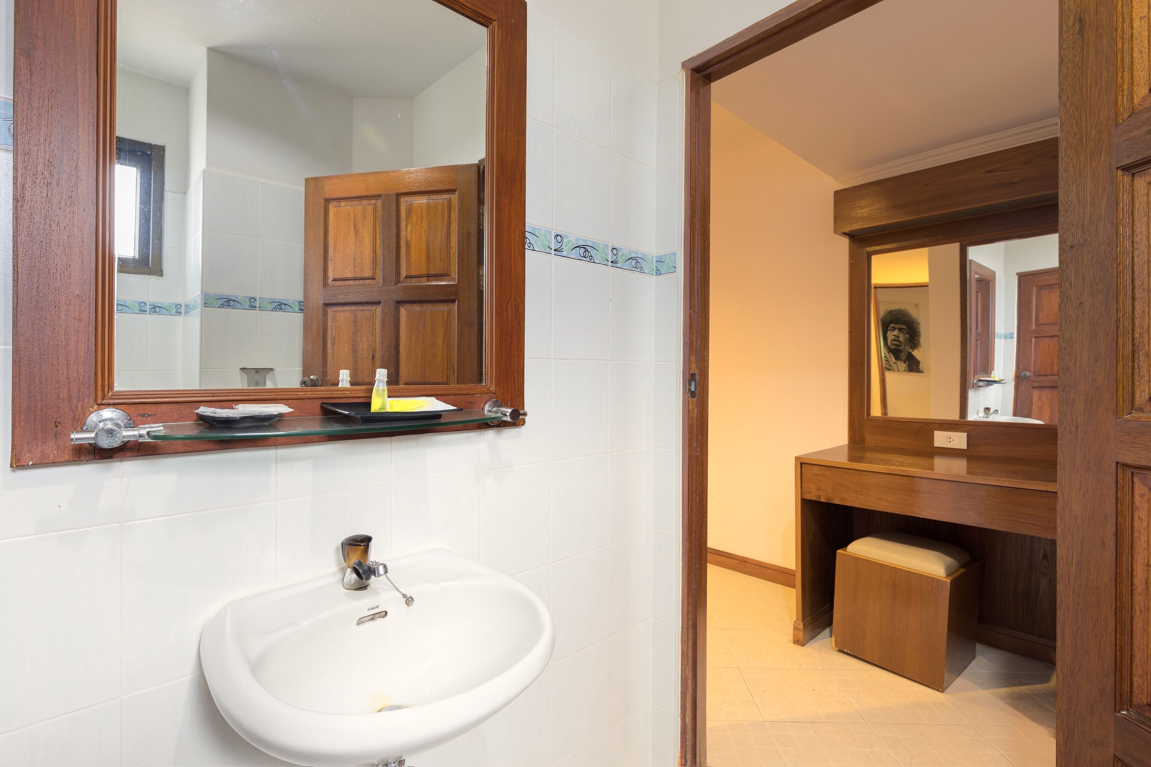 A bathroom with a white sink, a mirror, and a wooden vanity.
