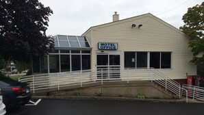 A building with a sign reading "Motel Office." It features a covered walkway with white railings and a staircase leading to the entrance. - Branford Motel (Branford)