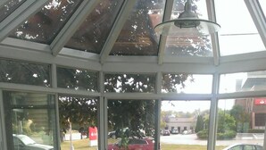 A conservatory with a glass ceiling, a patterned sofa set, and a small round table. - Branford Motel (Branford)