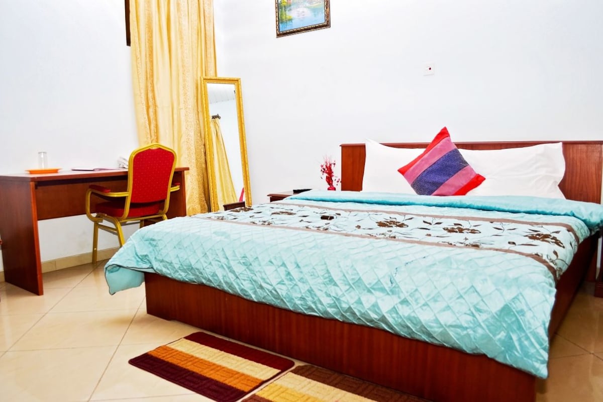 Ein Schlafzimmer mit Bett, Schreibtisch, Stuhl, Spiegel und Teppich.
