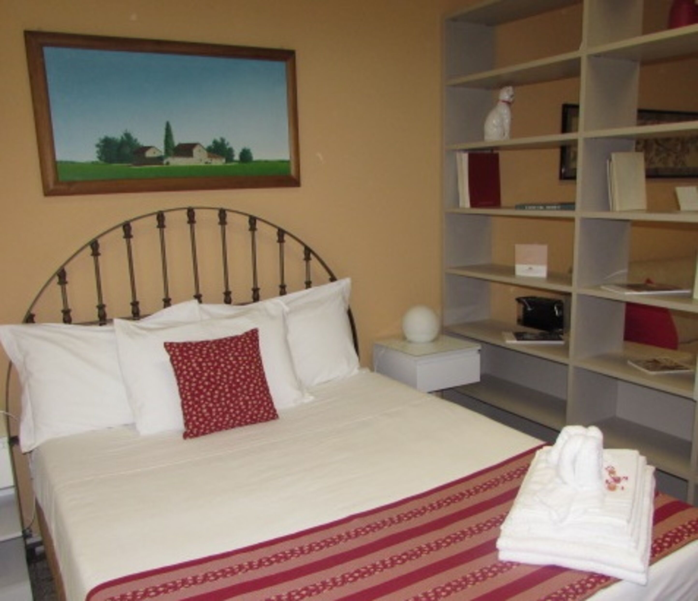 A neatly made bed with a patterned bedspread, a pillow, and a folded towel on a nightstand.