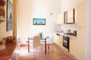 Una cucina compatta con zona pranzo, completa di fornello, forno e mobili.