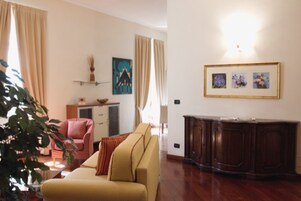 Una sala de estar con un sofá, una silla, un armario y un cuadro en la pared.