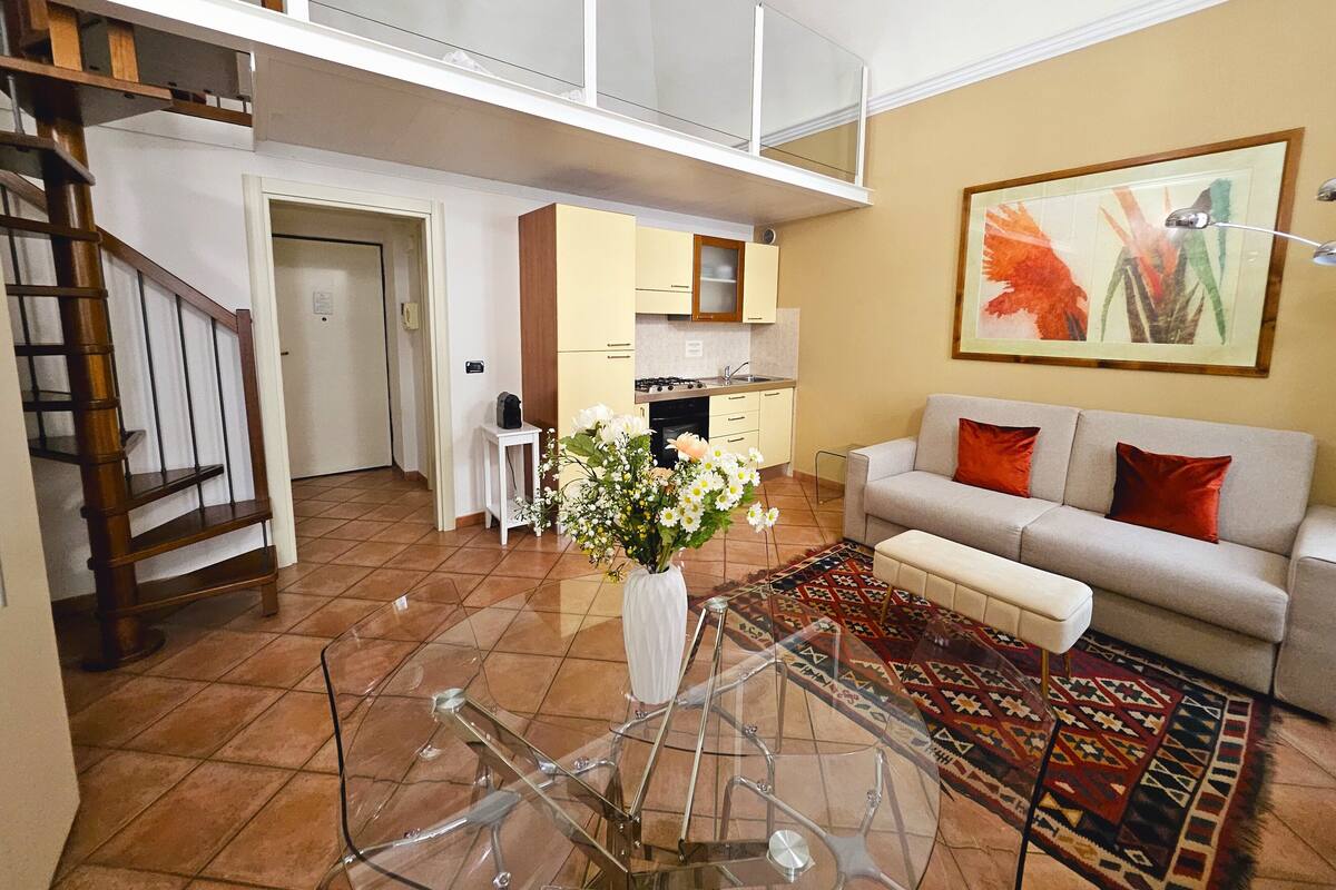 A spacious living area with a sofa, a coffee table, and a decorative vase with flowers.