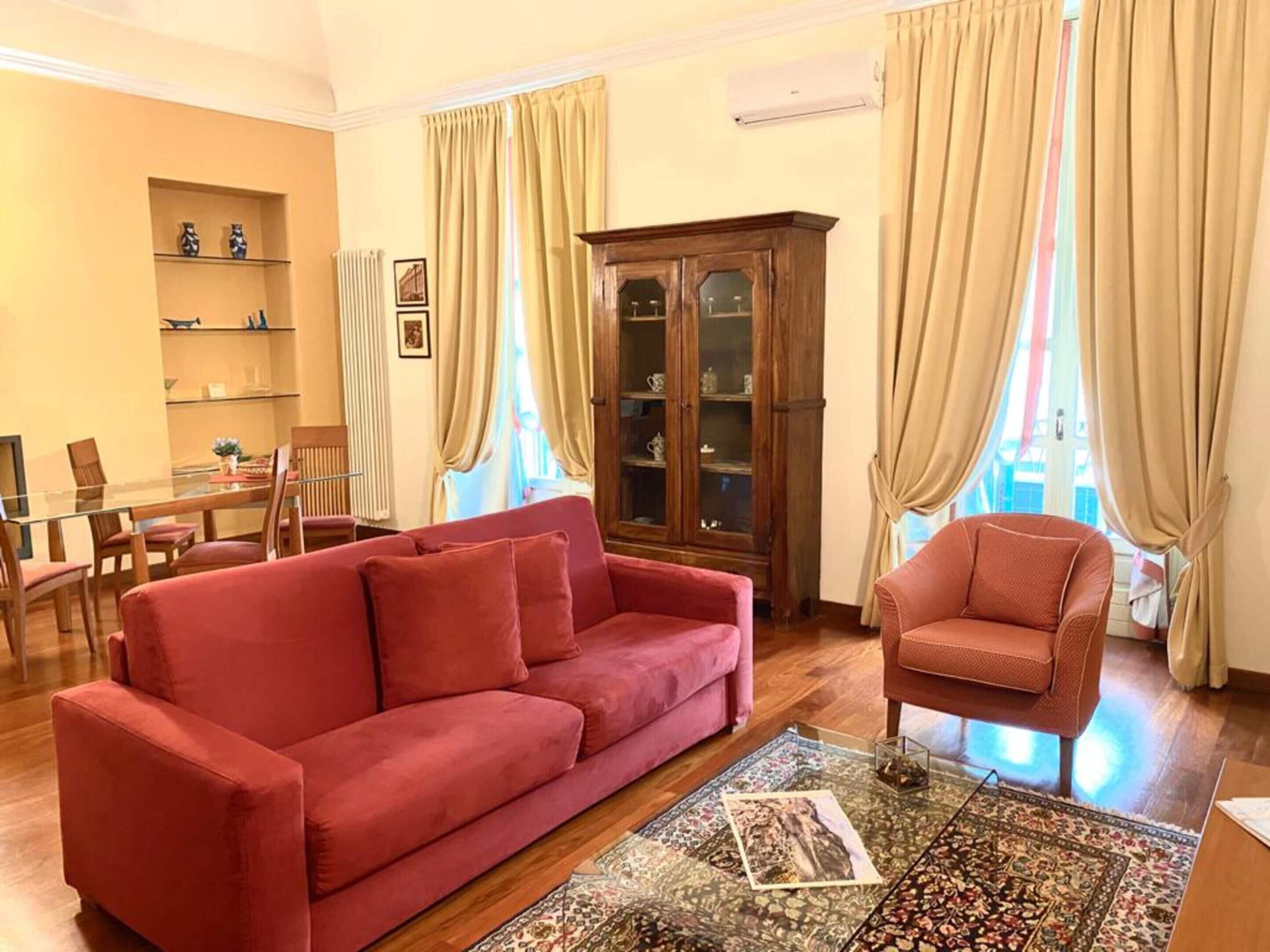 Un soggiorno con un divano rosso, un armadio in legno e un tappeto decorato.