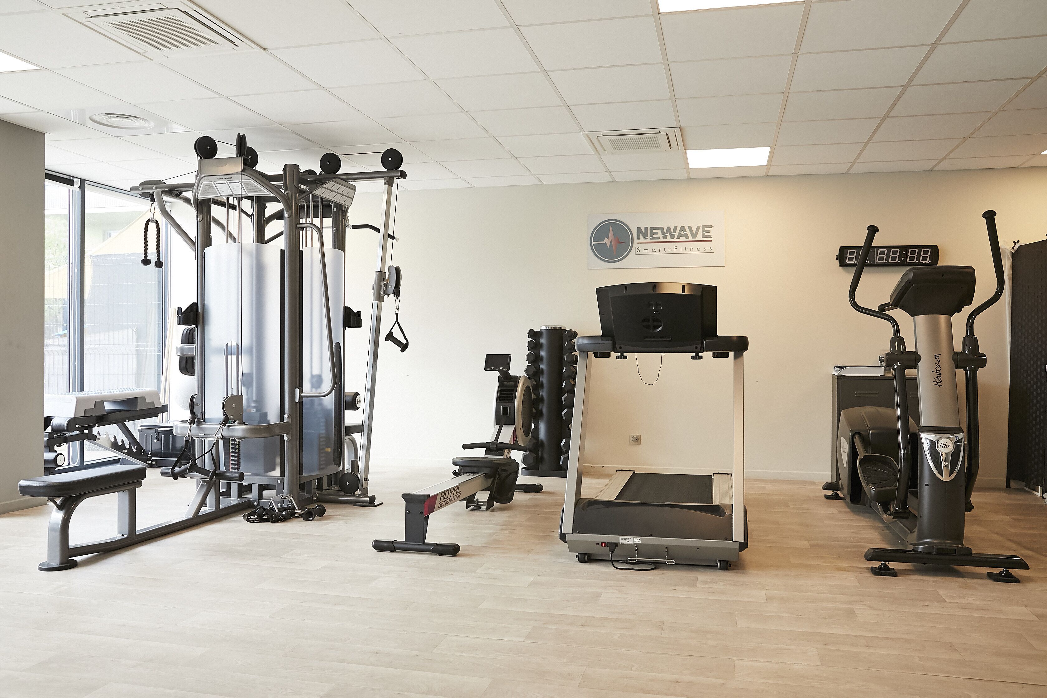 A gym with various exercise equipment, including a treadmill, elliptical, and weight machines.