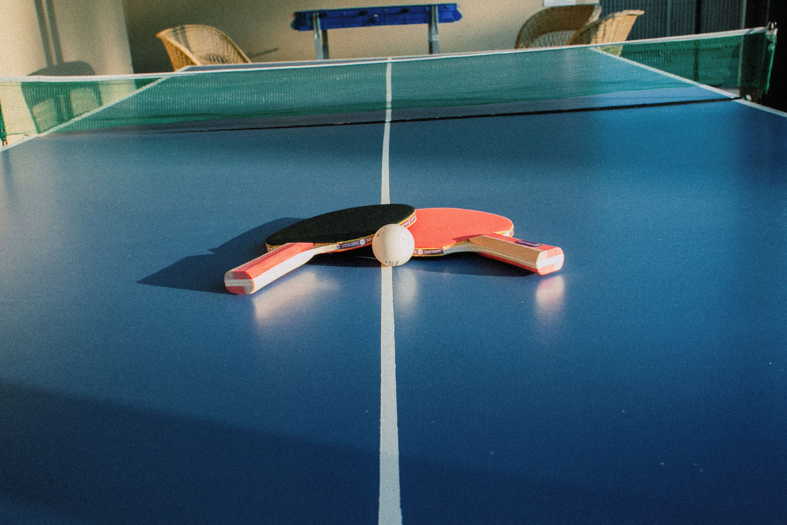 A ping pong table with paddles and a ball.