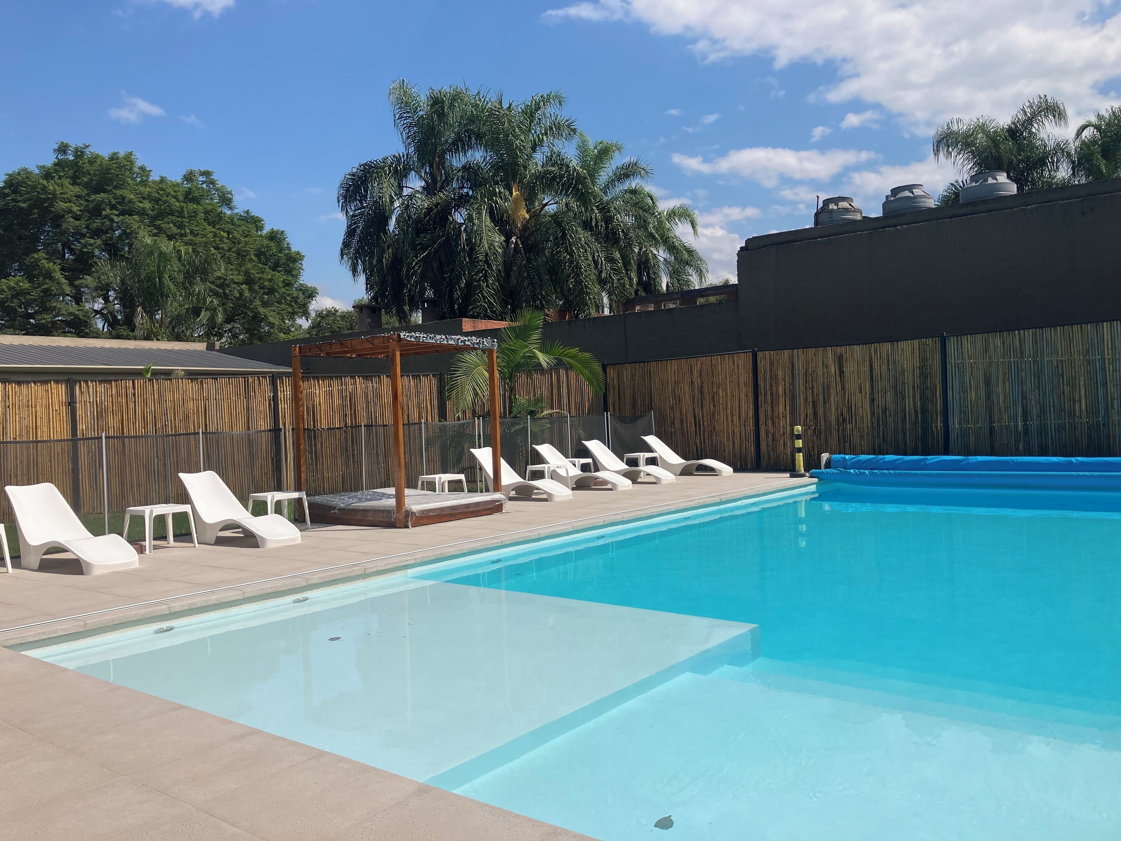 Una piscina con sillones de descanso y una pérgola de madera.
