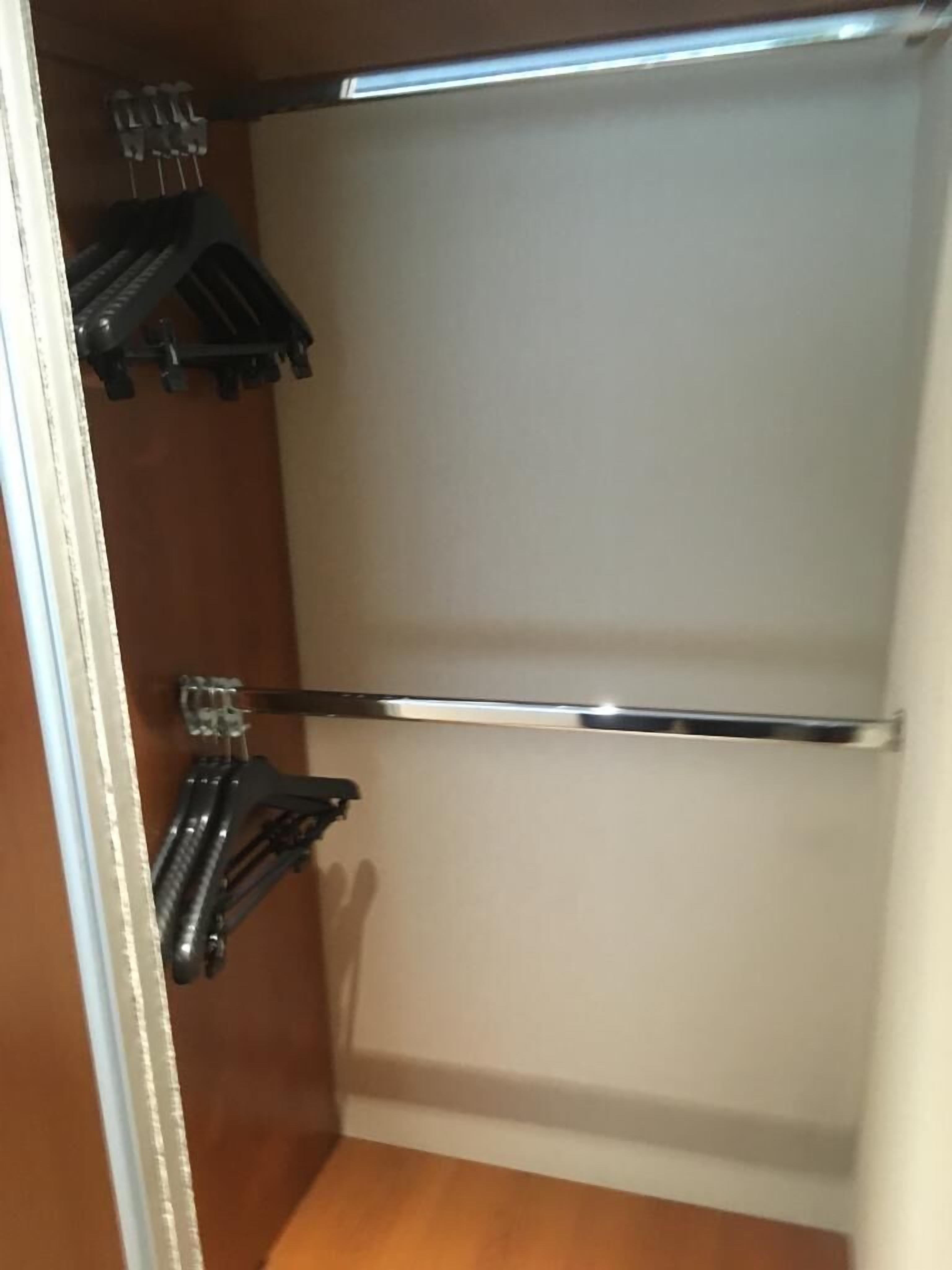Een kast met houten deuren, een kledingstang en een plank met haken.