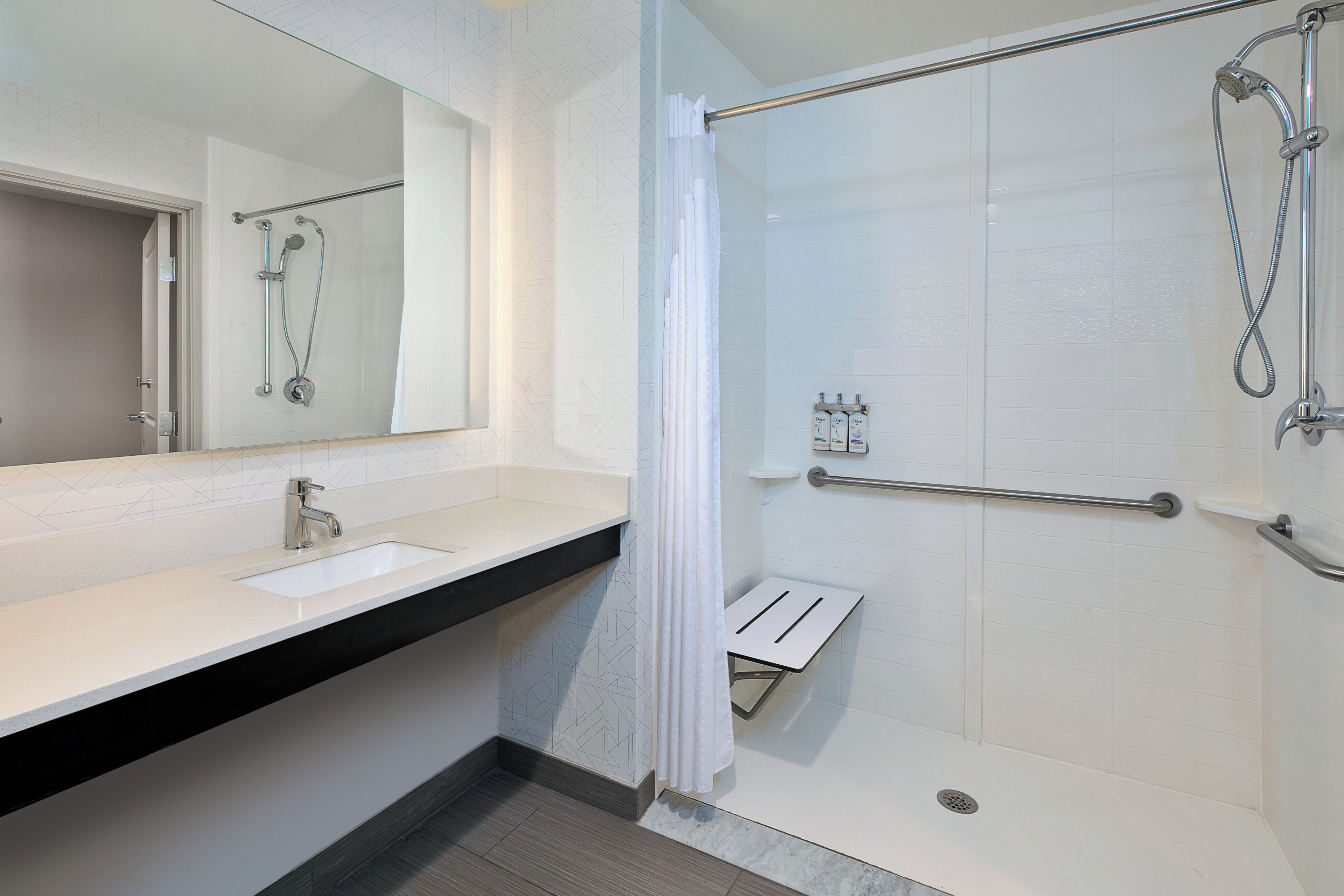 A modern bathroom with a shower, a sink, and a mirror.