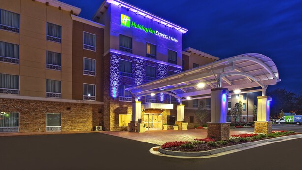 A Holiday Inn Express & Suites building with a brick facade, a covered entrance, and a parking area with a van in front. - Holiday Inn Express & Suites Ann Arbor West by IHG (Dexter)