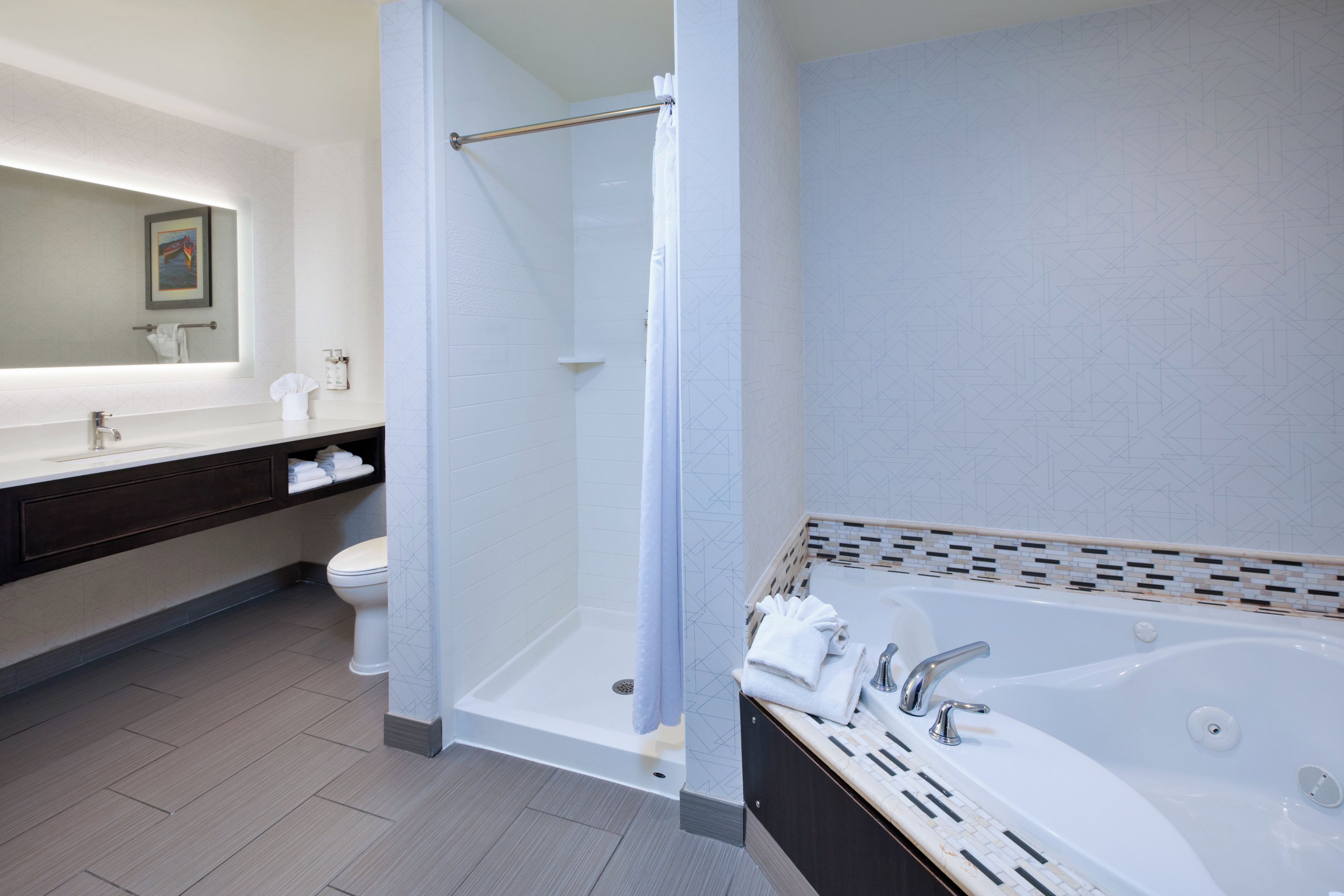 Une salle de bain moderne dotée d’une douche à l’italienne, d’une baignoire et d’un meuble-lavabo avec un miroir.