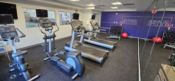 Un gimnasio con cintas de correr, elípticas y máquinas de pesas.