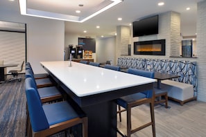 A conference room with a long table and chairs, a coffee station, and a fireplace. - Holiday Inn Express & Suites Ann Arbor West by IHG (Dexter)