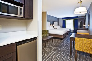 A hotel room with a bed, bedside tables, a microwave, a refrigerator, and a seating area with a chair and table. - Holiday Inn Express & Suites Ann Arbor West by IHG (Dexter)