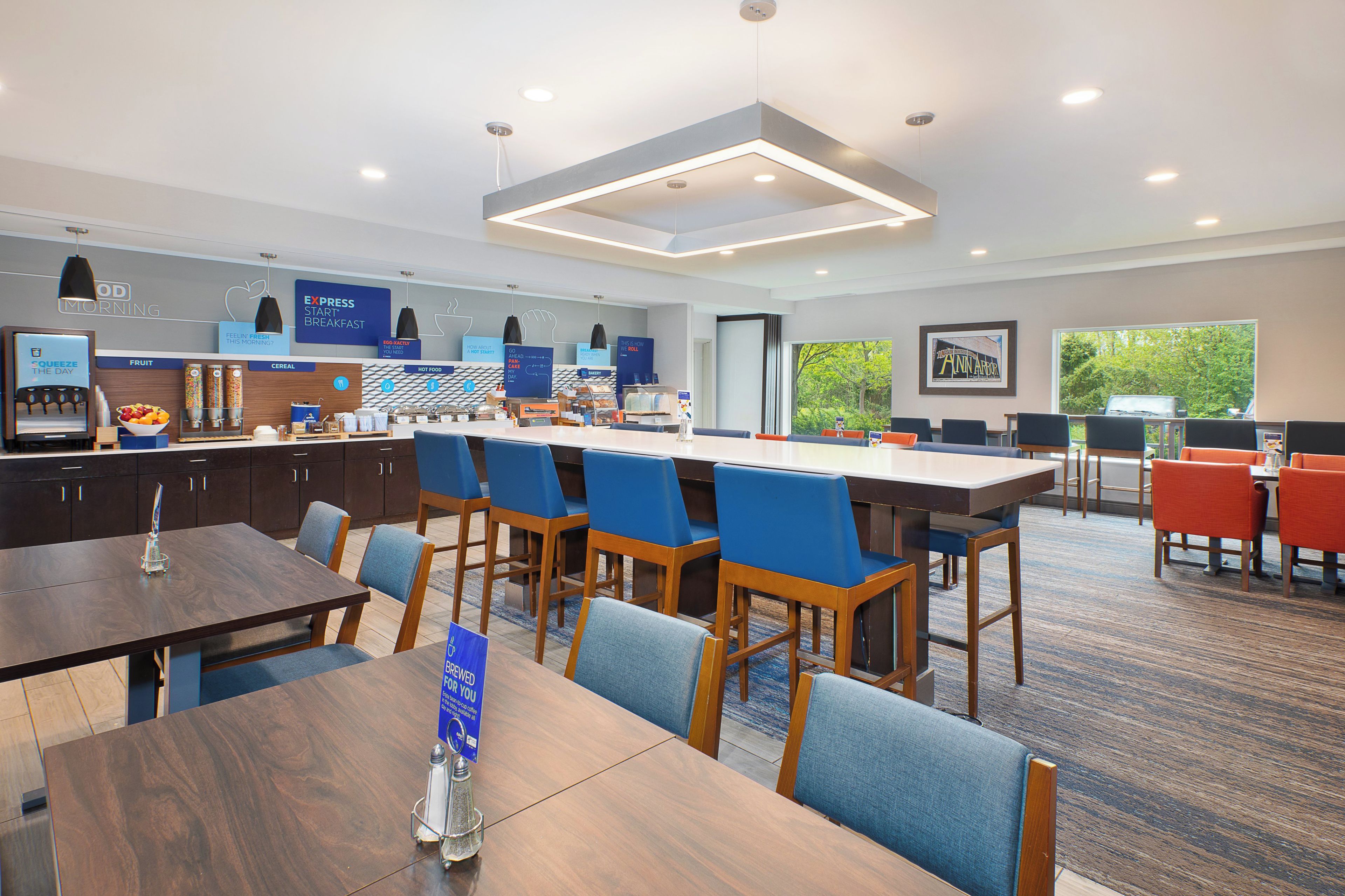 A modern breakfast area with a long counter, seating, and a view of the outdoors.
