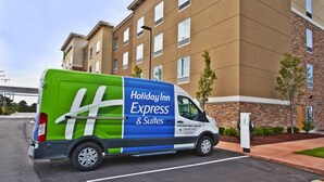 A Holiday Inn Express & Suites delivery van parked in front of a building with a brick facade and multiple windows. - Holiday Inn Express & Suites Ann Arbor West by IHG (Dexter)