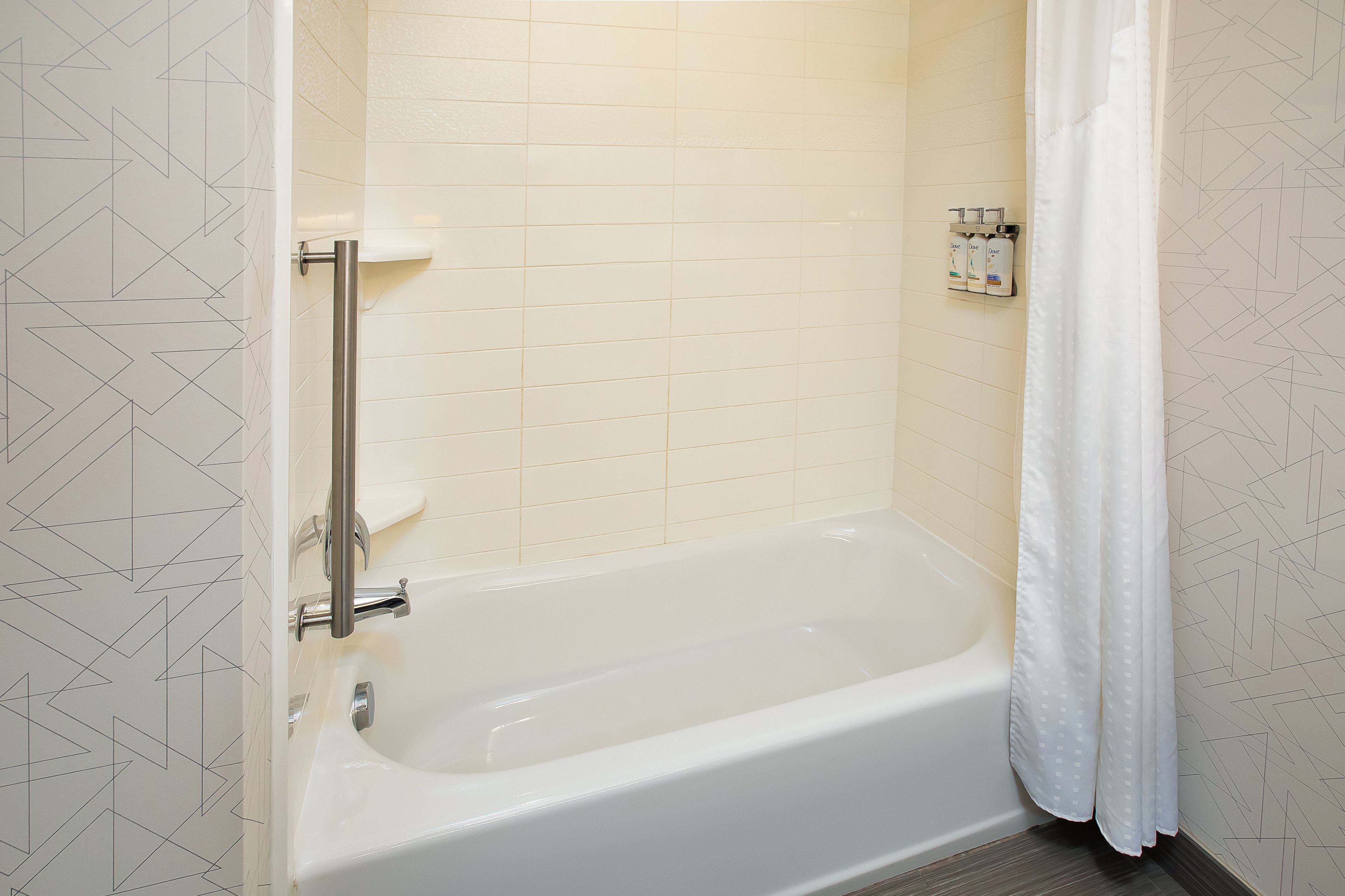 Une salle de bain avec une baignoire, un rideau de douche et une barre d’appui.