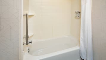 Une salle de bain avec une baignoire, un rideau de douche et une barre d’appui.