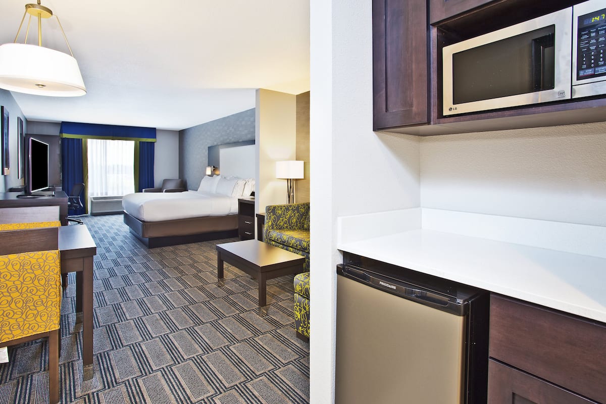 Une chambre d’hôtel équipée d’un lit, d’un bureau, d’une chaise et d’un four à micro-ondes placé au-dessus du comptoir.