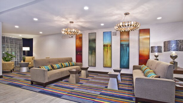 Un vestíbulo moderno con un sofá, sillones, una mesa de centro y una alfombra colorida a rayas.