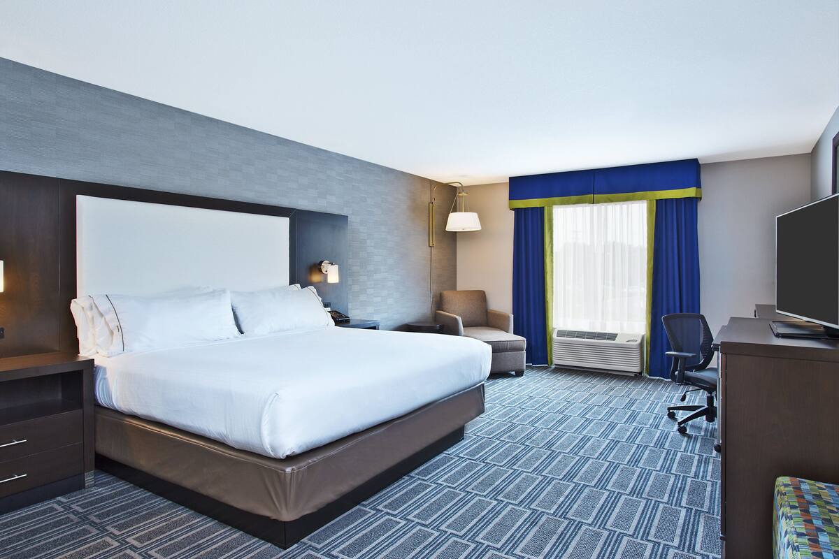 Une chambre d’hôtel avec un grand lit, un bureau, une chaise et un téléviseur.
