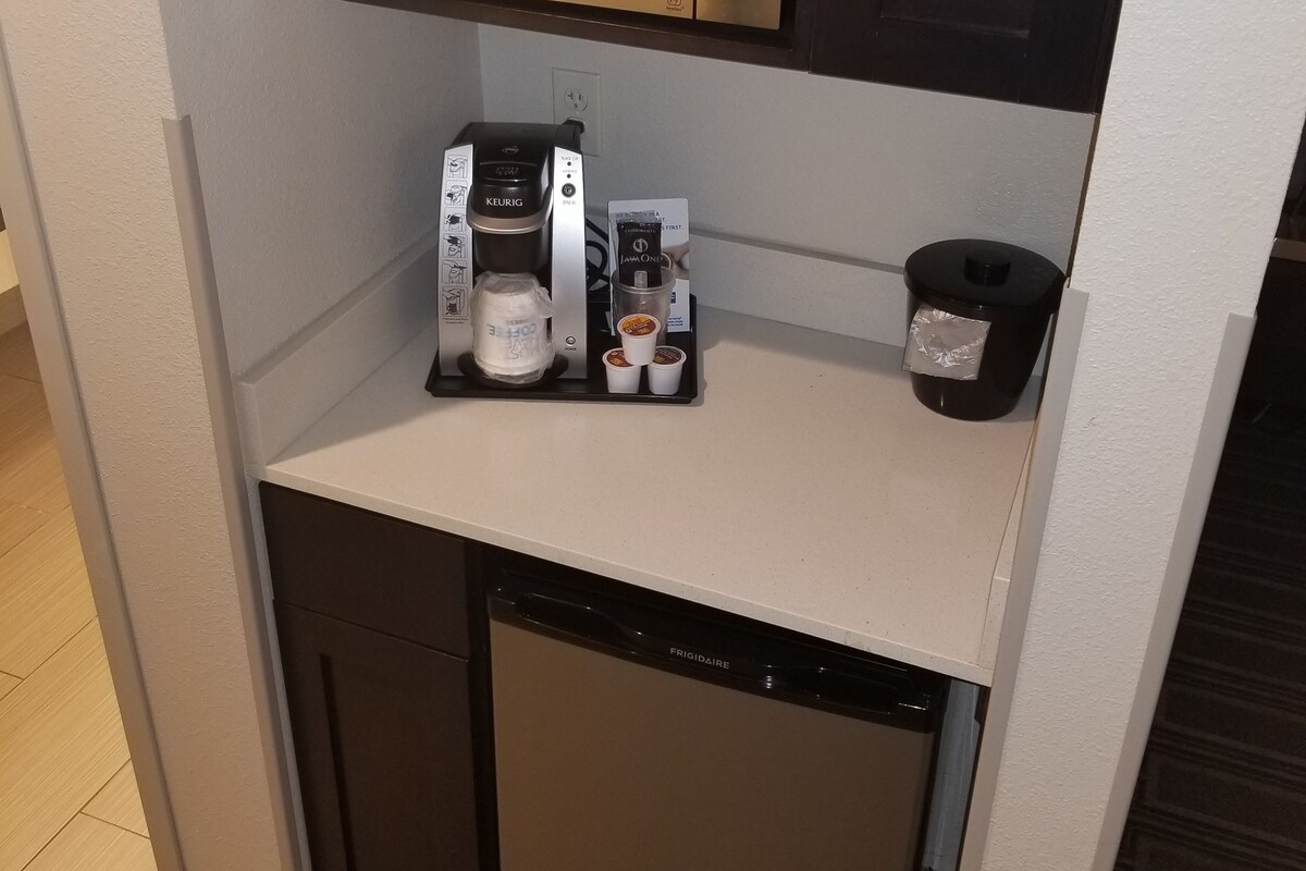 A compact kitchenette with a microwave, coffee maker, and dishwasher.