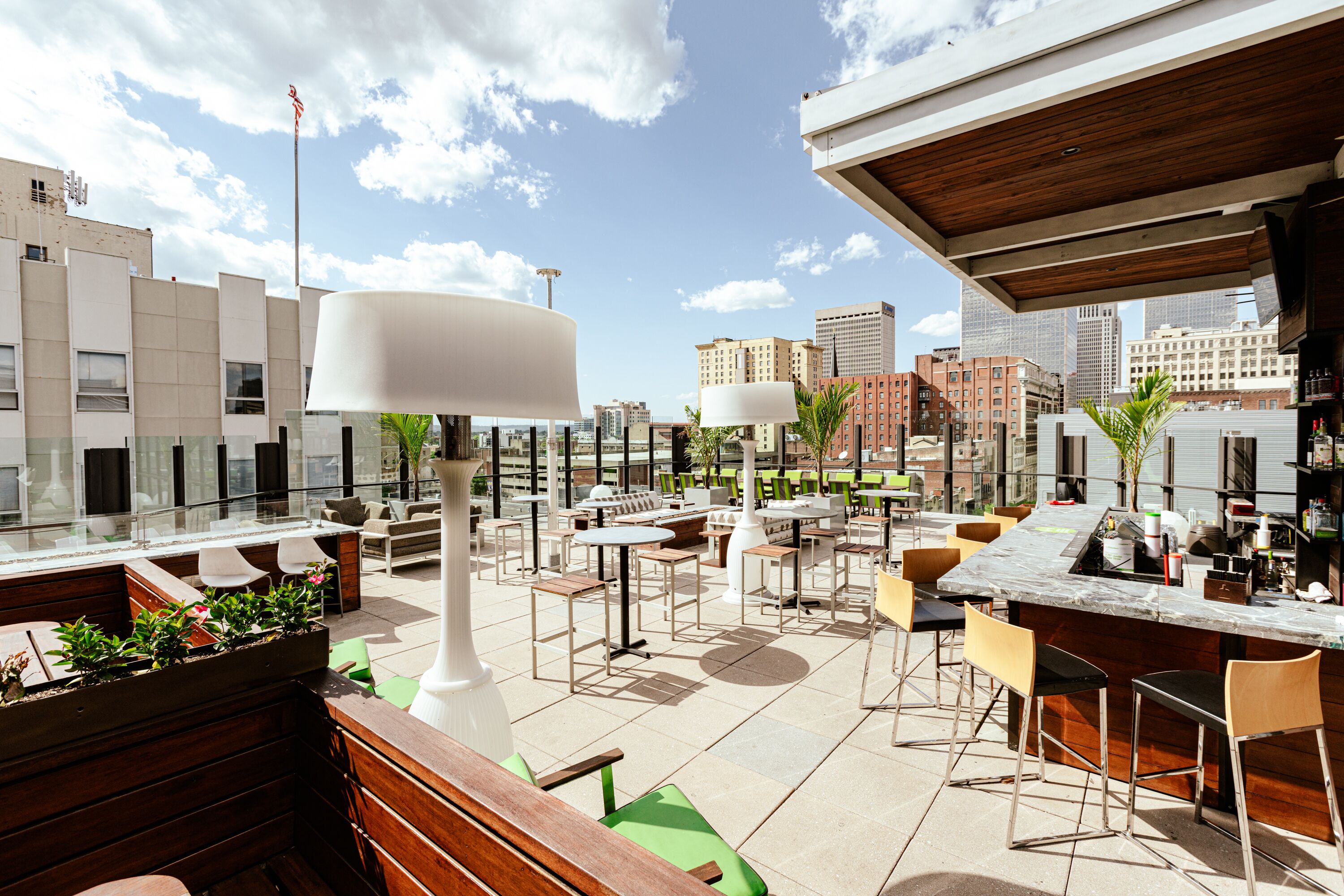 An outdoor seating area with tables and chairs, a bar, and a view of the city skyline.