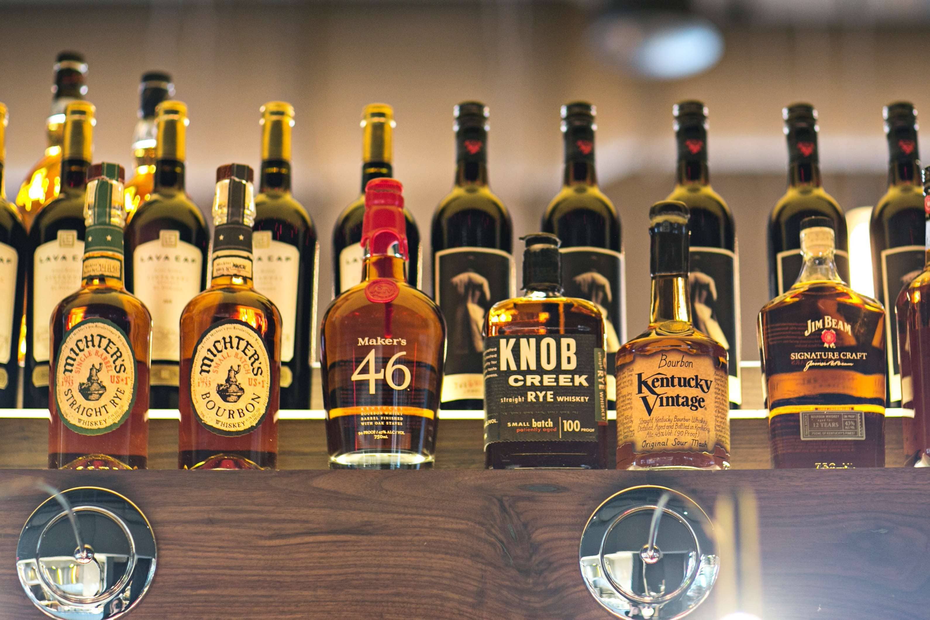 Diversas garrafas de whisky em uma estante de madeira.