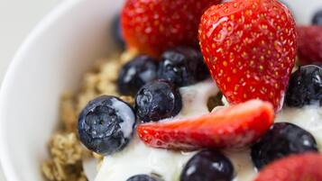 Un tazón de yogur con fresas y arándanos.
