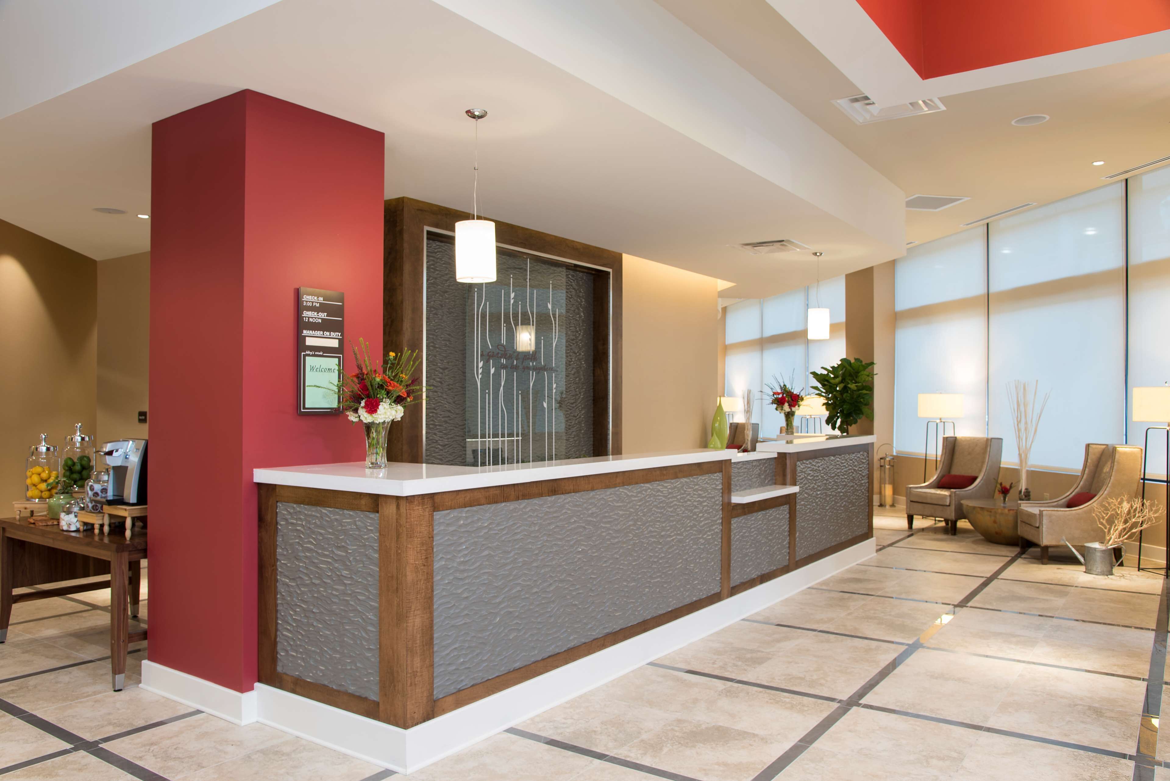 A reception area with a reception desk, a large window, and a seating area with chairs.