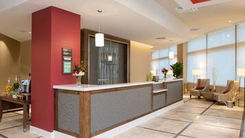A reception area with a reception desk, a large window, and a seating area with chairs.