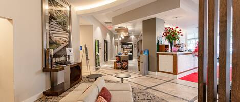 A spacious lobby with a modern sofa, a reception desk, and a large abstract painting.