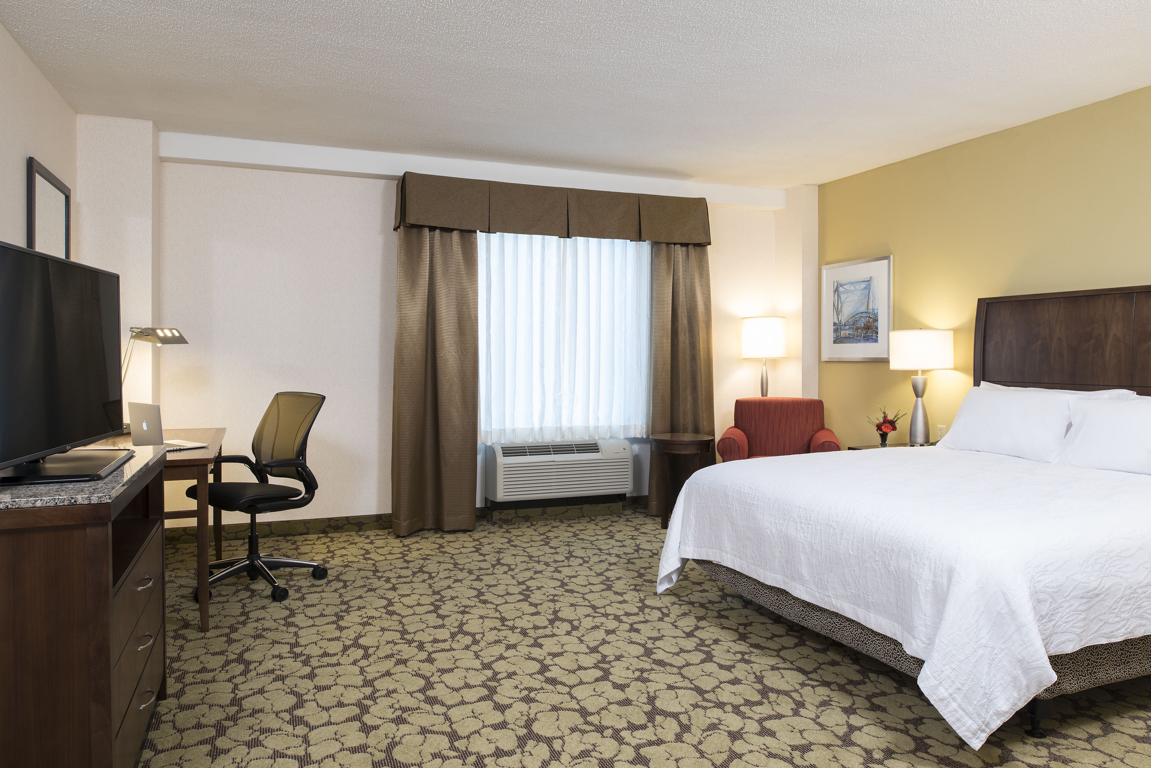 Une chambre d’hôtel équipée d’un lit, d’un bureau, d’une chaise, d’une télévision et d’un appareil de climatisation.