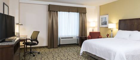 Une chambre d’hôtel équipée d’un lit, d’un bureau, d’une chaise, d’une télévision et d’un appareil de climatisation.