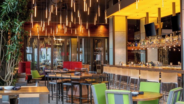 Un restaurante moderno con lámparas colgantes, una zona de bar y diversas opciones de asientos.