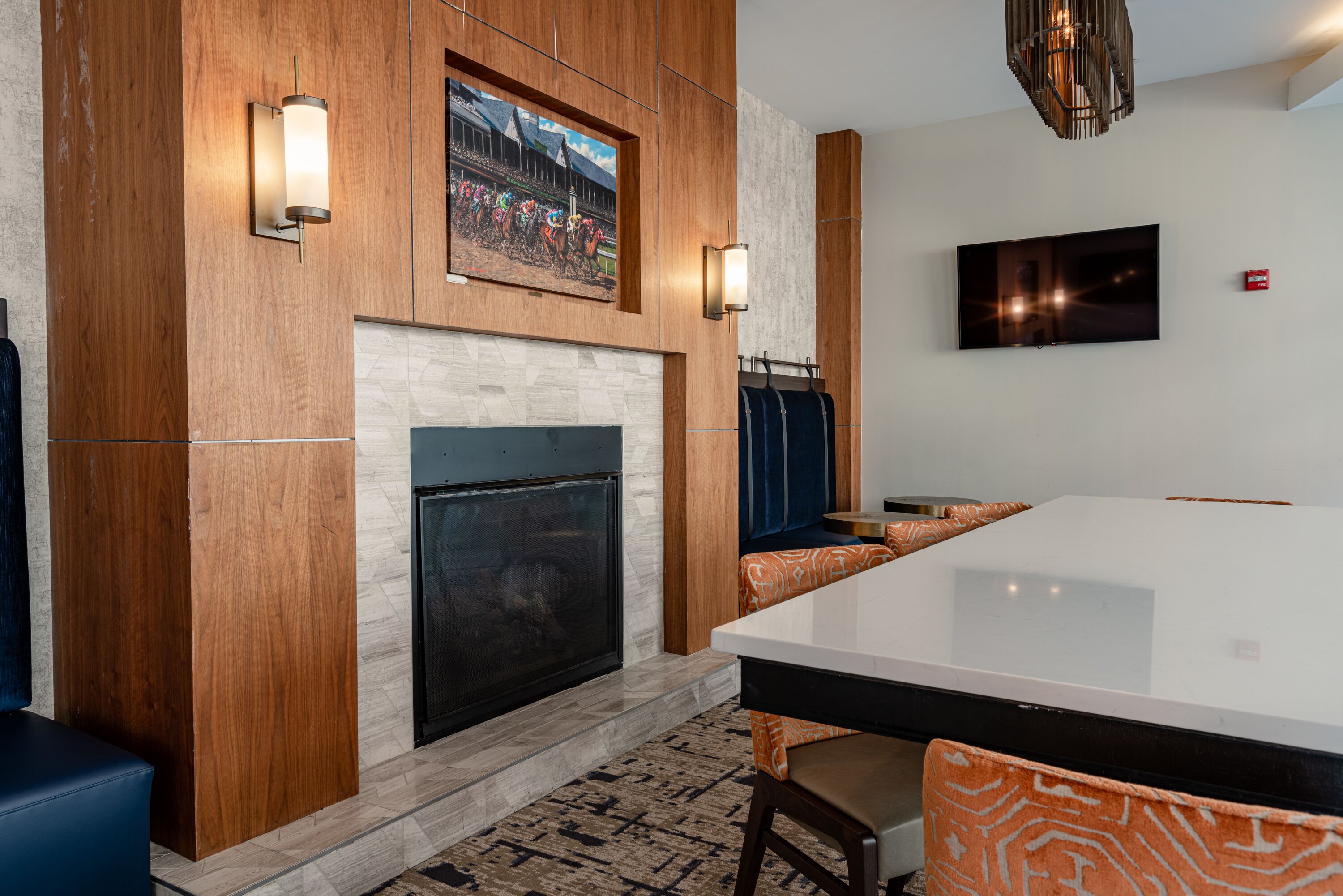 A modern room with a fireplace, a large flat-screen TV, wooden paneling, and a patterned rug.