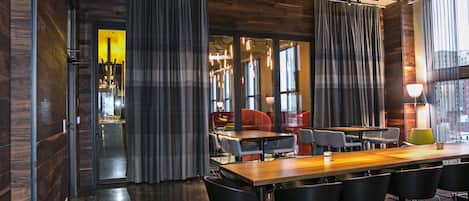 A modern conference room with a long table, black chairs, and a large window with curtains.