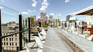 Una terraza en la azotea con mobiliario, vistas al horizonte urbano y arquitectura moderna.