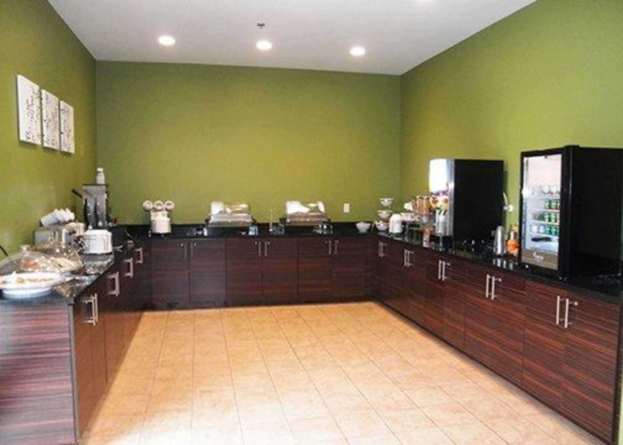 A spacious kitchen with dark wooden cabinets, a large island, and a green wall.
