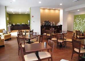 A restaurant with wooden tables and chairs, a counter with a menu, and a green wall with a white design. - Sleep Inn & Suites Belmont / St. Clairsville (Belmont)