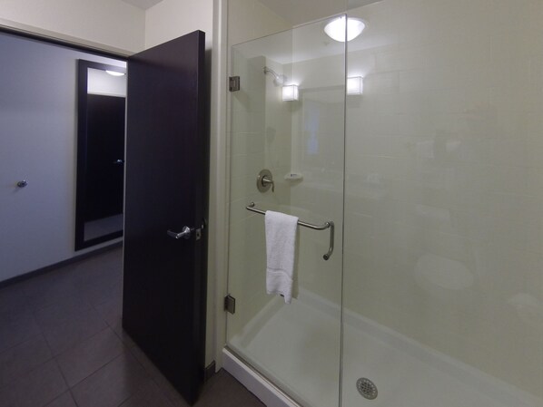 Un baño moderno con cabina de ducha de vidrio, un perchero y una puerta que da a otra habitación.