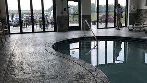 Une piscine intérieure offrant une vue dégagée sur l’extérieur, un poste de surveillance pour les sauveteurs et un panneau indiquant une profondeur de 4 pieds et 12 pouces.