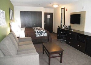 A hotel room with a bed, a sofa, a desk, a chair, and a TV. - Sleep Inn & Suites Belmont / St. Clairsville (Belmont)