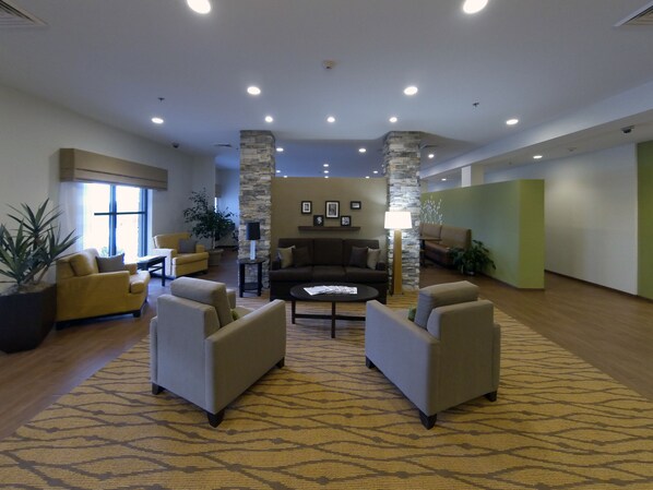 A spacious lobby with a central seating area, stone pillars, and a patterned carpet.
