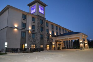 A hotel with a stone facade, multiple windows, and a covered entrance. - Sleep Inn & Suites Belmont / St. Clairsville (Belmont)