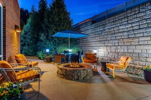 Un patio al aire libre con paredes de piedra, un hogar para fuego y sillas naranjas.