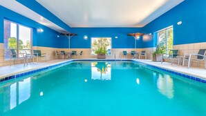 An indoor swimming pool with blue walls, clear water, and multiple lounge chairs around the perimeter. - Hampton Inn & Suites Parkersburg Downtown (Parkersburg)