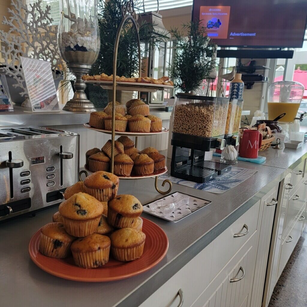 Un buffet con un'ampia scelta di prodotti da forno, tra cui muffin e pasticcini, e un angolo caffè con macchina e caraffa.